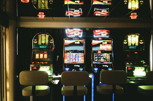 Máquinas tragaperras iluminadas en un casino español con juegos clásicos y jackpots disponibles online.